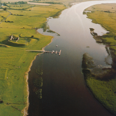 A broad river with fields either side, and an earthwork to one side of it.