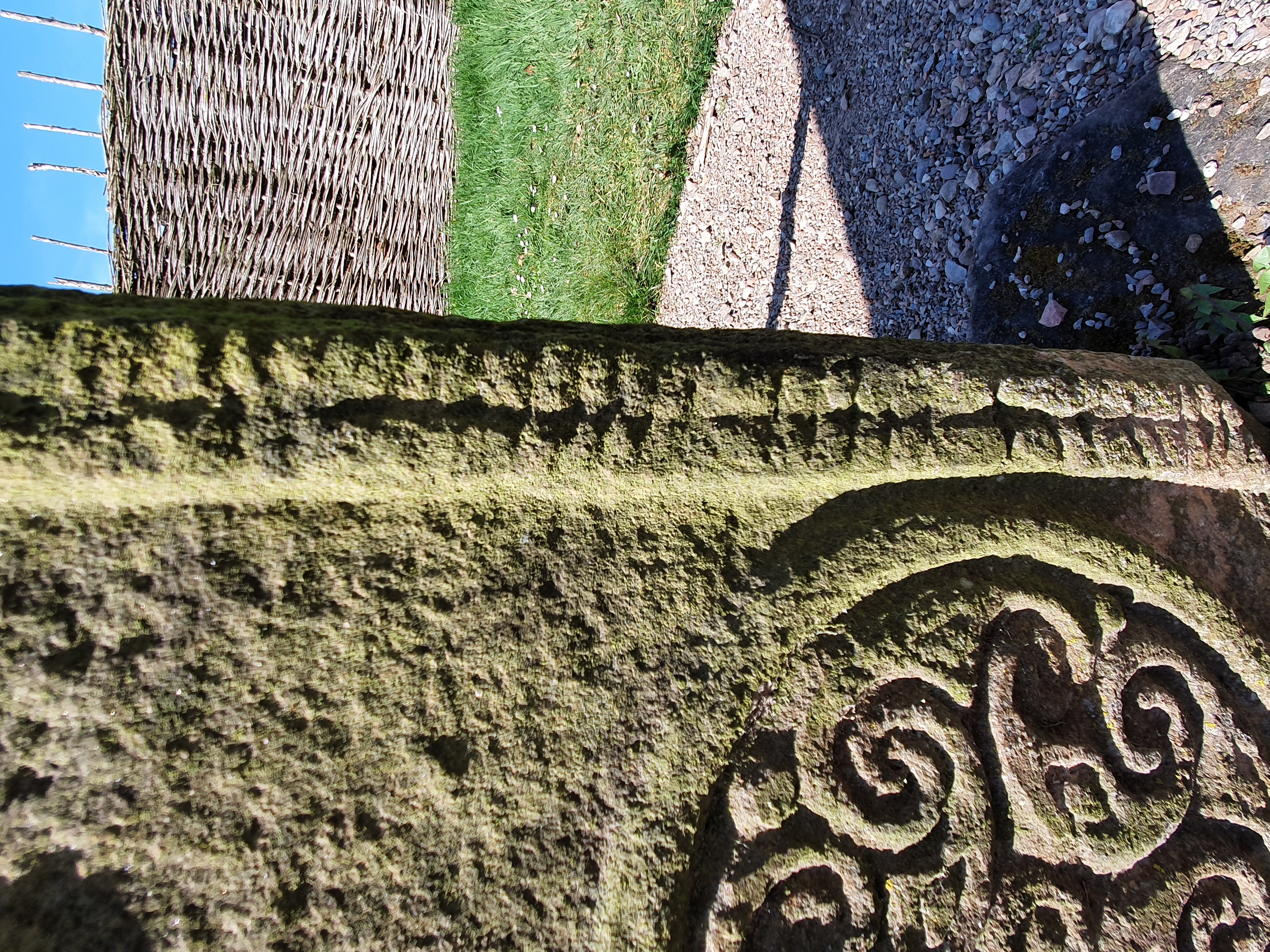Section of ogham script, comprised of notches along a stem line, inscribed into the edge of the symbol-bearing face of Rodney’s Stone