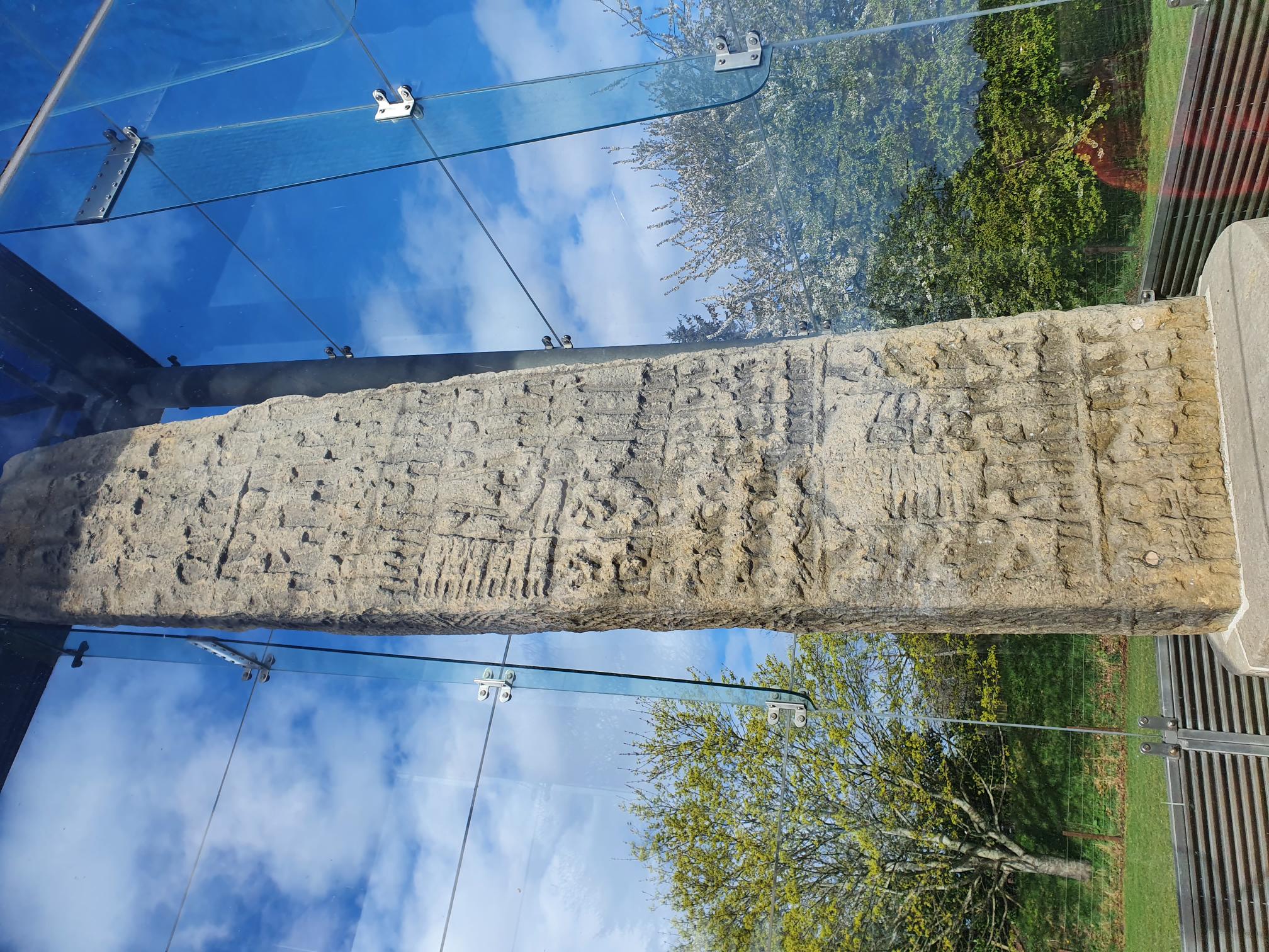 Photograph of the east face of Sueno's Stone, with rows of figures including riders, footsoldiers, sword combat, decapitated bodies and severed heads.